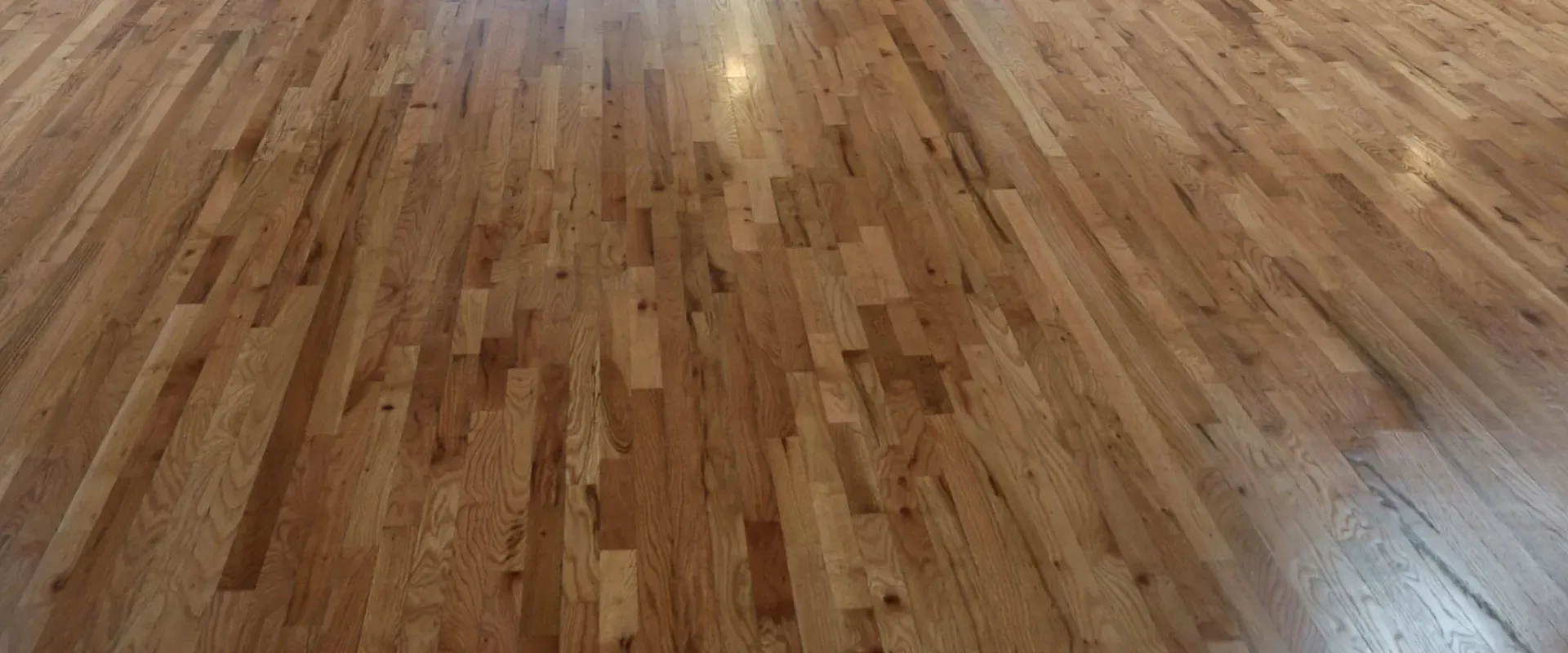 Tight crop of the original hardwood floor at Sterling Event Space, oblique angle, warm grain visible.
