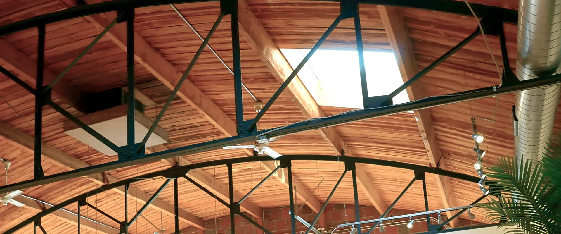 Close detail of a steel truss at its junction with the tongue-and-groove wood barrel vault ceiling.