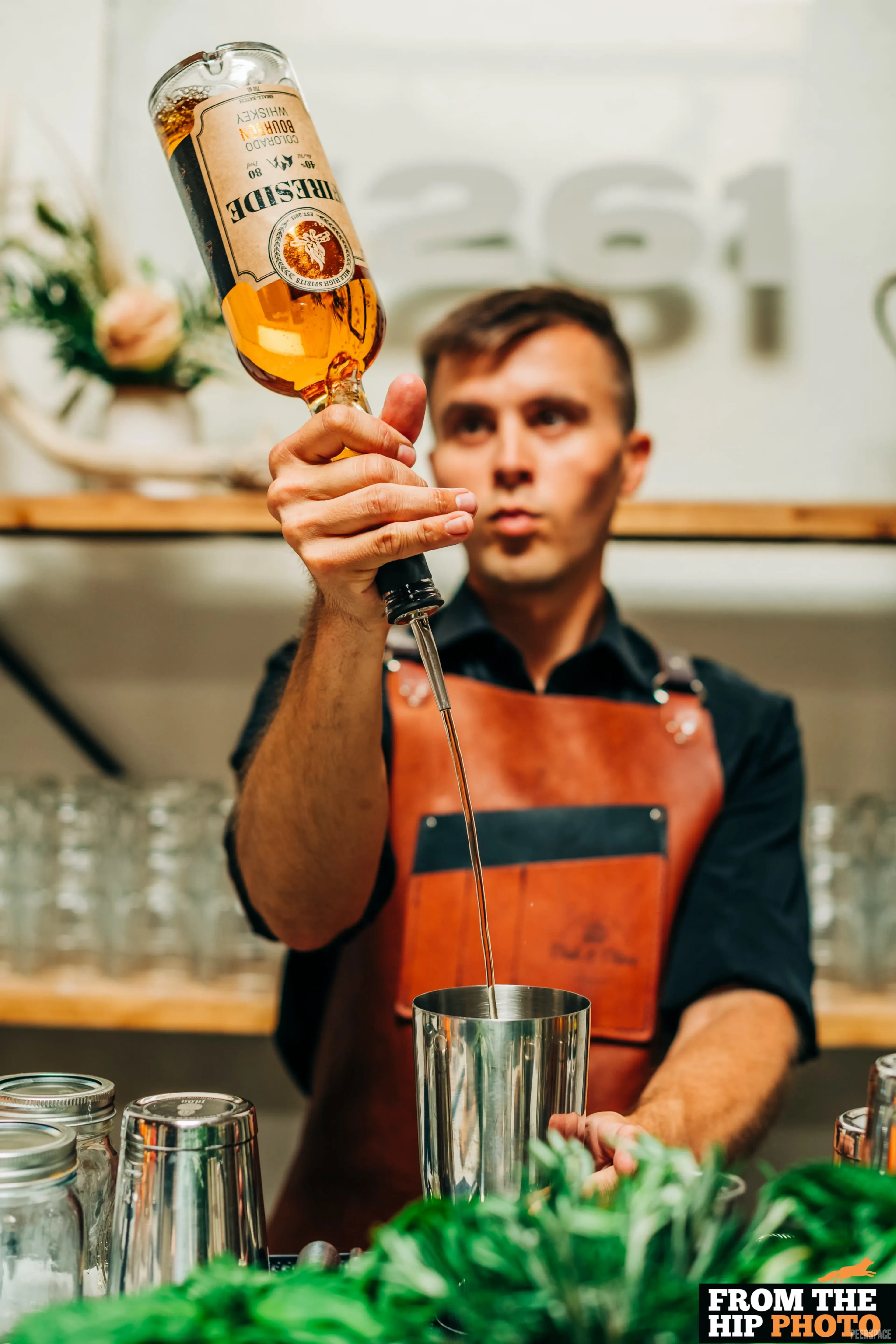 Editorial lifestyle portrait of a bartender at Sterling, with the 1261 sign visible in soft focus behind.
